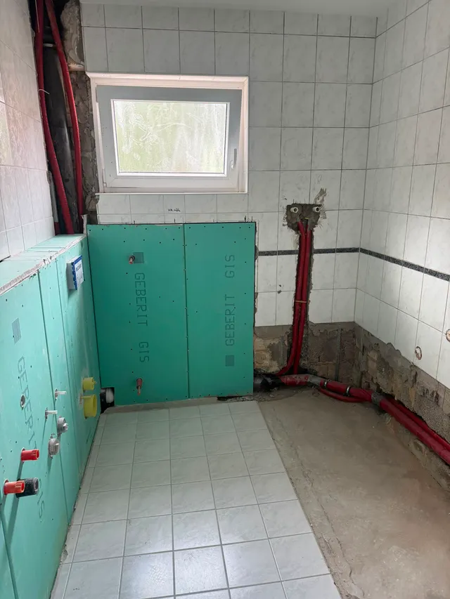 Vorwandinstallation über Eck bis unter das Fenster, mit herausstehenden Wasser- und Abwasseranschlüssen