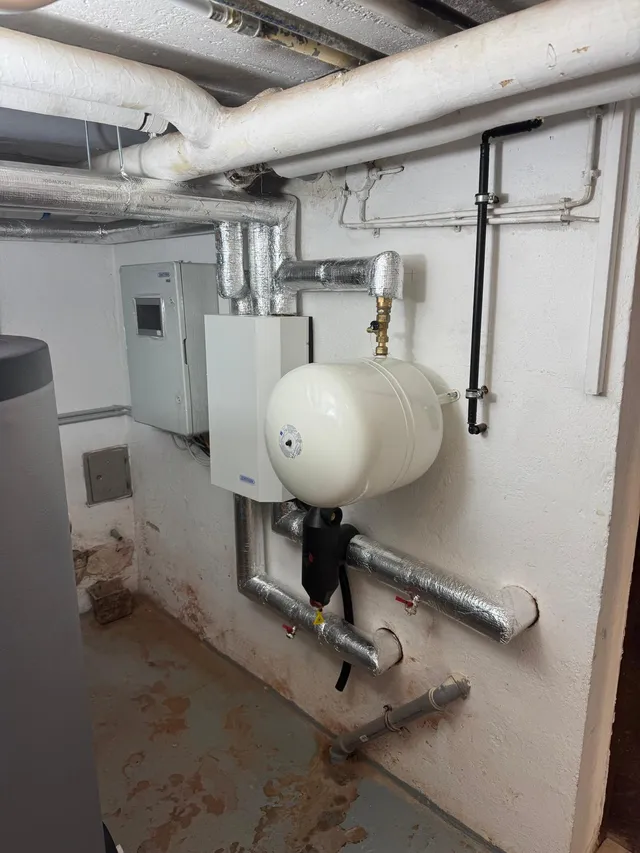 Wandmontiertes Hydraulikmodul mit Ausdehnungsgefäß und gedämmten Vor- und Rücklaufleitungen im Keller